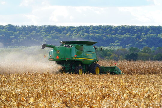 Farmers on the countryside used a John Deere combine with corn head harvested corn feed.