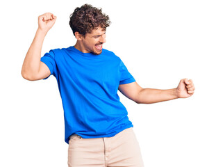 Young handsome man with curly hair wearing casual clothes dancing happy and cheerful, smiling...