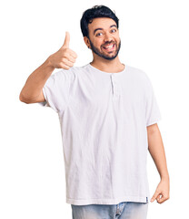 Young hispanic man wearing casual clothes smiling happy and positive, thumb up doing excellent and approval sign