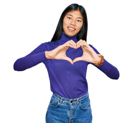 Beautiful young asian woman wearing casual clothes smiling in love doing heart symbol shape with hands. romantic concept.