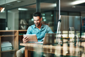 The digital worker gets things done. Shot of a young businessman using a digital tablet at his desk in a modern office.