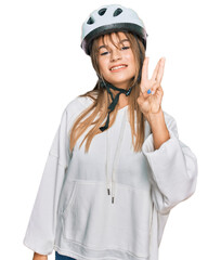 Teenager caucasian girl wearing bike helmet showing and pointing up with fingers number three while smiling confident and happy.