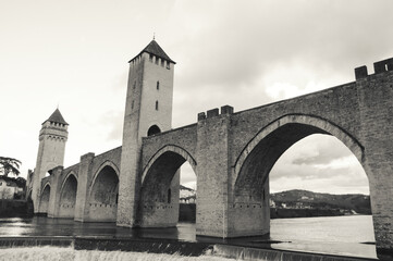 Fototapeta na wymiar Cahors, France. Valentre bridge with its picturesque towers over Lot river at sunset. Valentre Bridge is part of the Santiago Pilgrim route and listed as UNESCO World Heritage Site. Black white photo