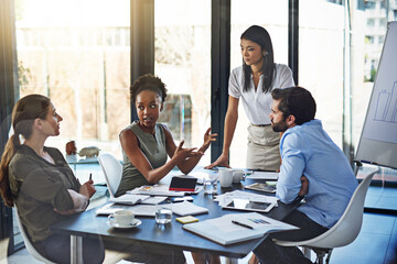 Putting their heads together as a team. Shot of a group of businesspeople having a meeting in a...