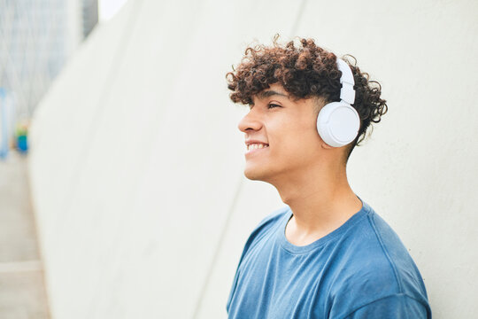 Portrait Of A Hispanic Teenager Listening To Music With Headphones