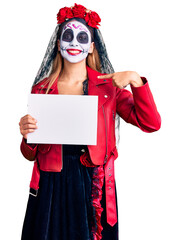 Woman wearing day of the dead costume holding blank empty banner pointing finger to one self smiling happy and proud