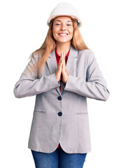 Beautiful young woman wearing architect hardhat praying with hands together asking for forgiveness smiling confident.