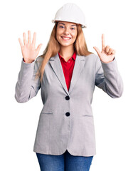 Beautiful young woman wearing architect hardhat showing and pointing up with fingers number seven while smiling confident and happy.