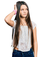 Fototapeta premium Young brunette girl with long hair wearing white shirt confuse and wondering about question. uncertain with doubt, thinking with hand on head. pensive concept.