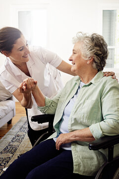 Shes so good with her patients. Shot of a smiling caregiver helping a senior woman in a wheelchair at home.