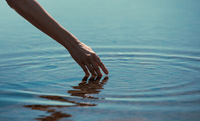 hands touching calm water making ripples 