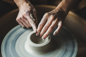Potter's hands working with raw clay making potttery, ceramic studio workshop, traditional craft 