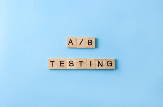 Words A B testing on wooden blocks with letters on blue background. Product development process concept.