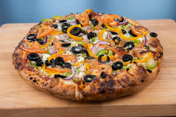 A delicious freshly baked greek pizza with feta cheese, olives, tomato, and green pepper.