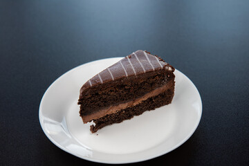 Chocolate cake on white plate on black background