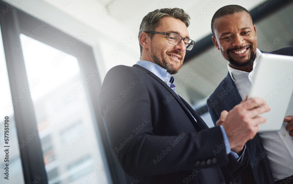 Poster Trading business knowledge with ease thanks to wireless technology. Shot of two businessmen using a digital tablet together at work.