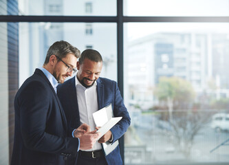 Improving professional performance with the latest apps. Shot of two businessmen using a digital...
