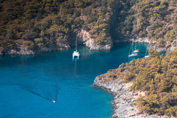 Azure sea bay, blue ocean gulf with white yachts. Backpack path in tropical mountains.  blue sunny sky on the horizon. Start of the adventures on the trail. Semi-desert landscape and fir trees.