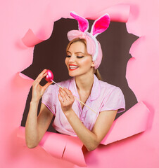 Happy easter day. Smiling woman in bunny ears painting Easter egg. Bunny girl with painted eggs for...