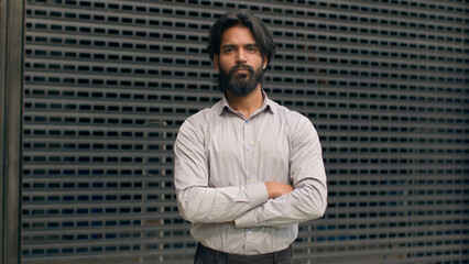 Successful smiling indian businessman posing indoors with crossed arms confident executive man professional manager look at camera arabian bearded male young company leader feel motivated hands folded