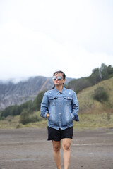 View of Mount Bromo.  female tourist wearing black glasses and blue jean jacket enjoying the beauty of mount bromo in indonesia