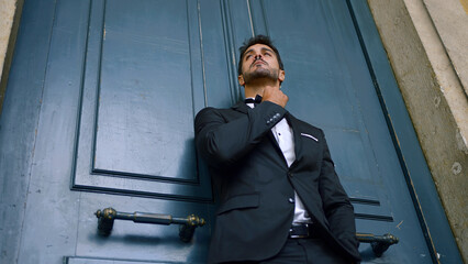 Young man with beard and in suit stands attractively against wall. Action. Elegant hot man in suit...