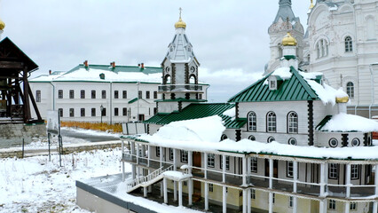 Obraz premium Calm snowy landscape. Clip.View from a height of the white temples standing next to the houses against the backdrop of the village and the blue sky.