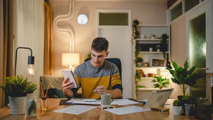 Young caucasian man teenager student study at home at the table night