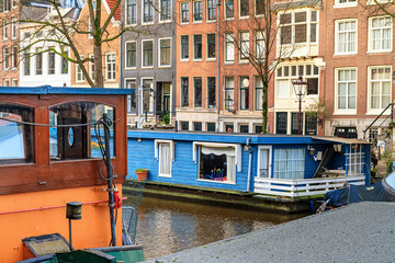 Cityscape on a sunny winter day - view of the water canal with houseboats in the historic center of Amsterdam, the Netherlands