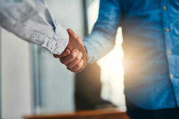 Lets shake on it. Closeup shot of businesspeople shaking hands in an office.