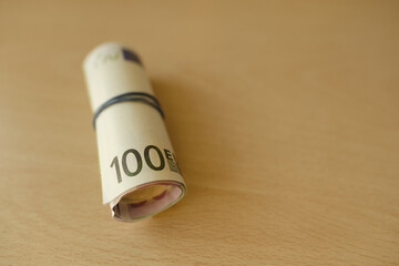 paper 100 euro banknotes rolled into tube on blurred creamy background, payments to fund, salary, gift for holiday, social assistance poor, save up for vacation, car, winnings, get passive income