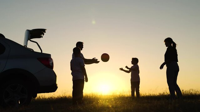 Travelling by car, Family play. Dad with child son, mother, children play with ball, toy plane, next to car, beautiful sunset. Happy family travels by car. Parents, children stopped at campsite by car