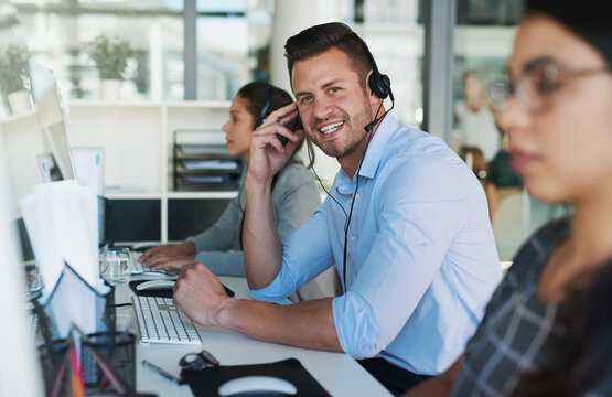 Customer care you can count on. Portrait of a happy and confident young man working in a call center.