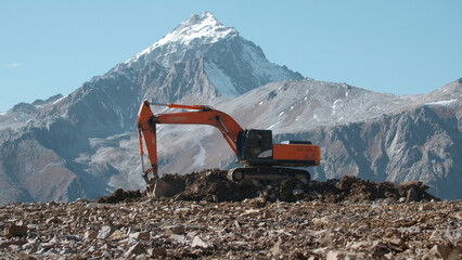 Excavators working in mountains. Creative. Excavator is working on rocky mountainside. Heavy machinery working in mountains © Media Whale Stock