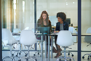 Making sense of their ideas. Shot of colleagues working together on a laptop in a modern office.