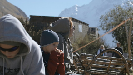 Family with child is sitting on pass in mountains. Creative. Family on trip is resting in mountains. Family with boy sitting on rise in mountains