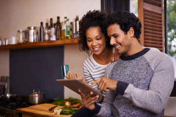 Obraz premium Lets download this recipe. Shot of a young couple using their tablet together while they get ready to prepare a meal.