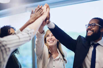 We did it, together. Low angle shot of a group of young businesspeople high fiving in celebration...