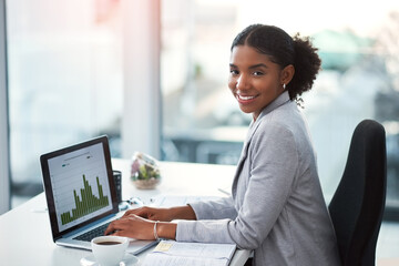 Just call me the financial guru. Shot of a young businesswoman using a laptop with graphs on it in...
