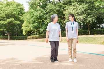 公園で運動・ウォーキング・歩く高齢者と介護士・看護師・理学療法士・運動指導員の女性
