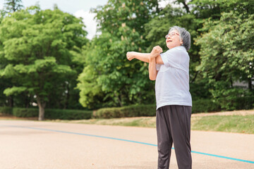 公園で運動・体操・ストレッチする高齢者女性
