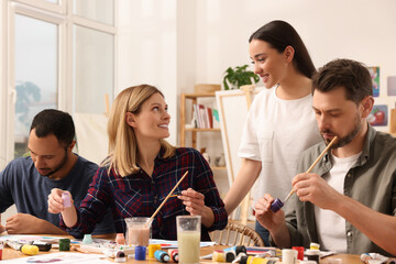 Fototapeta premium Artist teaching her students to paint at table in studio. Creative hobby