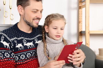Happy man receiving greeting card from his daughter at home