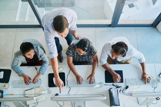 Quality customer service is a team effort. High angle shot of a man assisting his colleagues in a call center.