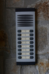 Modern intercom on concrete wall with stone fragments. Security system