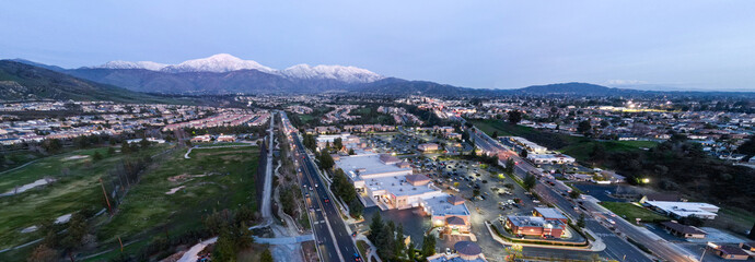 An Aerial View of the Sun Going Down over Yucaipa, California, with a Super market Shopping Complex and Traffic Below