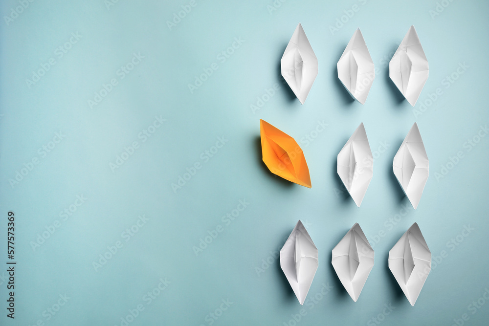 Poster Yellow paper boat floating away from others on light background, flat lay with space for text. Uniqueness concept