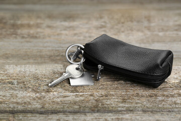 Leather case with key on old wooden table, closeup. Space for text