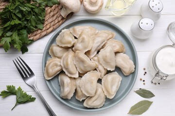 Delicious dumplings (varenyky) with potatoes served on white wooden table, flat lay