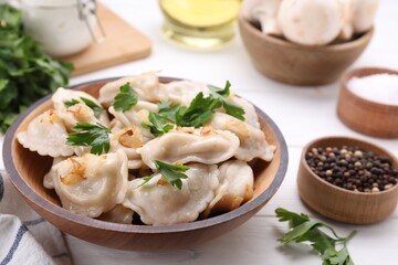 Delicious dumplings (varenyky) with potatoes, onion and parsley served on white wooden table